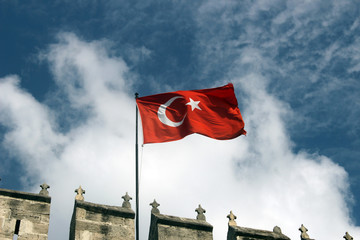 The flag of Turkey waving in the wind over blue sky.