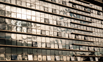 Clouds reflected in windows of modern office glass building. Bus