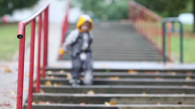 Little boy, jumping in muddy puddles in the park, going down stairs