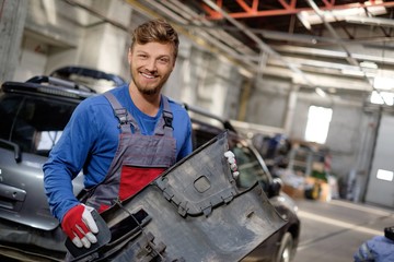 Fototapeta premium Mechanic with car bumper in a workshop