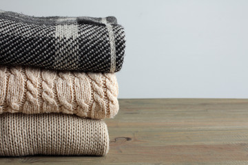 Fototapeta na wymiar stack of warm sweaters on wooden table on grey background