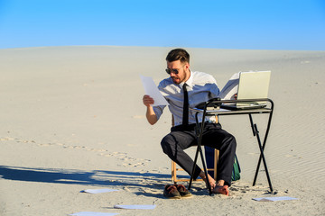 Businessman using  laptop in a desert