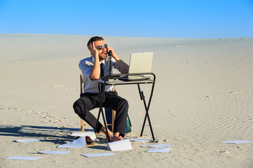 Businessman using  laptop in a desert