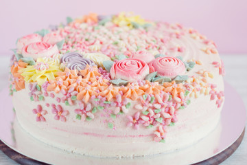 Obraz na płótnie Canvas Pastel pink cake decorated with cream flowers