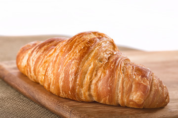 Whole flaky french croissant on a board isolated