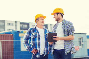 smiling builders in hardhats with tablet pc