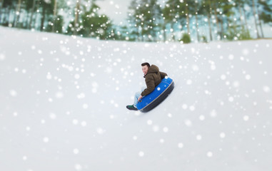 happy young man sliding down on snow tube