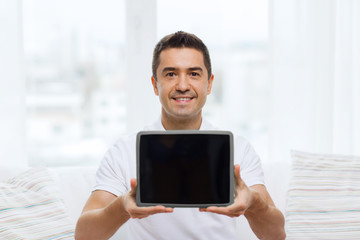 smiling man showing tablet pc blank screen at home
