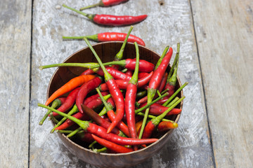 Hot red chilli in a bowl and on a wooden floor.