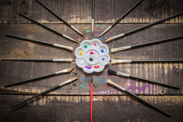 Paint brushes set and a palette with oil paint tubes on wooden background