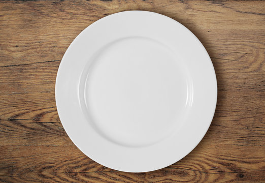white dinner plate on wooden table top view