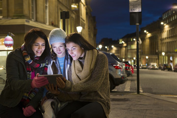 Obraz na płótnie Canvas Three women looking at a digital tablet in the city