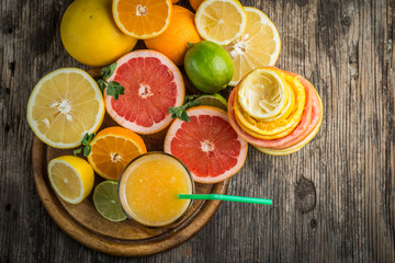 Fototapeta na wymiar Juice glass and fresh citrus fruit on rustic wood.Fresh healthy