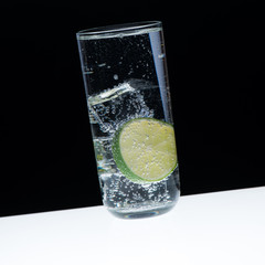 Glass, ice, lemon and indian tonic/close-up with black backgroun