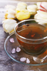 Cup of herbal tea with tulips on wooden table, closeup