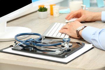 Doctor working at table in office
