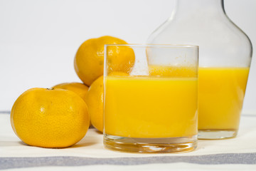 Glass of natural tangerine orange juice on white
