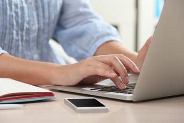 Woman using laptop on workplace close up