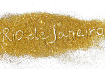Blurry inscription Rio de Janeiro on golden glitter sparkles on white background
