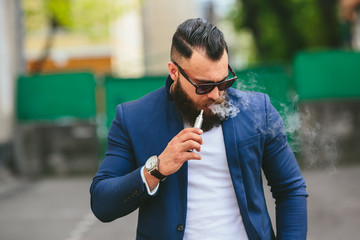 man with a beard smokes electronic cigarette