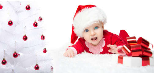 Beautiful little baby celebrates Christmas. New Year's holidays. Baby in a Christmas costume with gift. Christmas tree