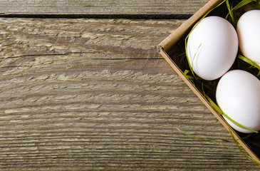 White fresh eggs in cardboard box with grass