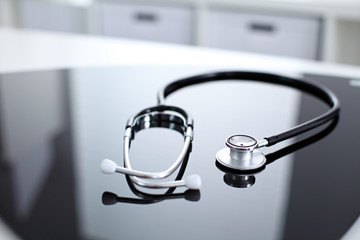 Stethoscope on black, reflective background
