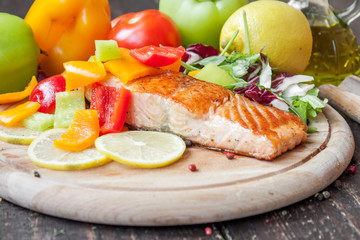 Fried salmon with vegetables on a wooden table