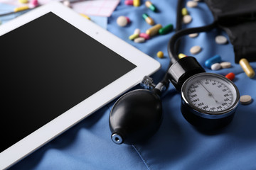 Blood pressure meter, stethoscope, digital tablet on dark background