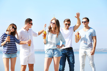Obraz premium Young people with beer on the riverside