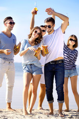 Young people with beer on the riverside