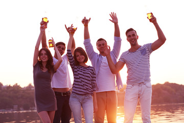 Obraz premium Young people with beer on the riverside