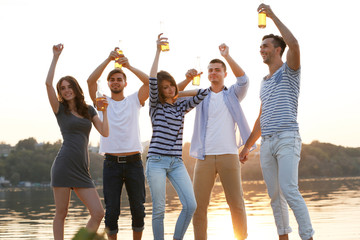 Young people with beer on the riverside