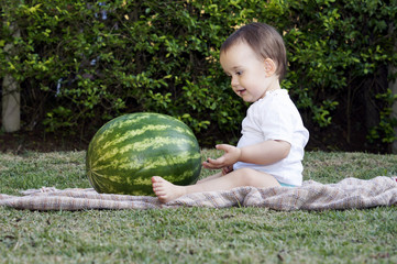 Fototapeta premium Baby looking and playing with a watermelon