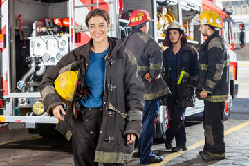 Happy Firewoman With Colleagues Discussing By Truck
