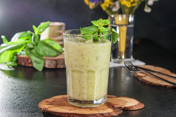 Glass of healthy green vegetable smoothie on the wooden board on dark background