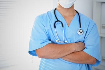 Portrait of unknown male surgeon doctor holding his stethoscope, crossed arms