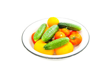 tomatoes and cucumbers on a dish on white