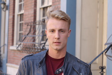 close portrait of handsome adult blonde man, with blured urban classic background