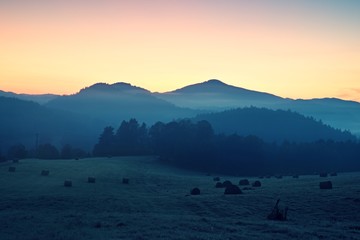 Early autumn  morning in meadows, hoarfrost on grass in  foggy valley