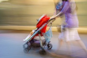 Mom rushes through town with a blurred stroller late for, what?
