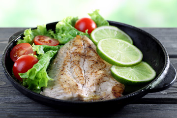 Dish of fish fillet with salad and lime on table close up