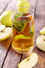 Glass of apple juice with fruits and fresh mint on table close up