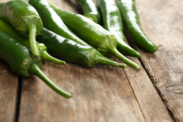 Green hot peppers on wooden table close up
