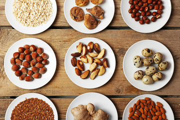 Different products on saucers on wooden table, top view