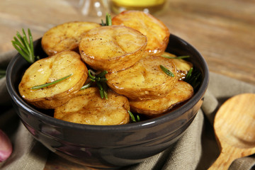 Delicious baked potato with rosemary in bowl on table close up