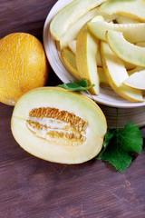 Ripe melons with green leaves on wooden table close up