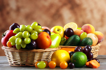 Heap of fresh fruits and vegetables in basket on wooden table close up