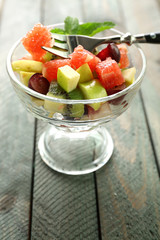 Fruit salad in glass bowl, on wooden background