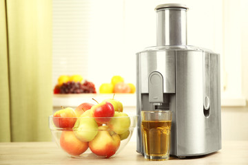 Juicer and apple juice on kitchen table